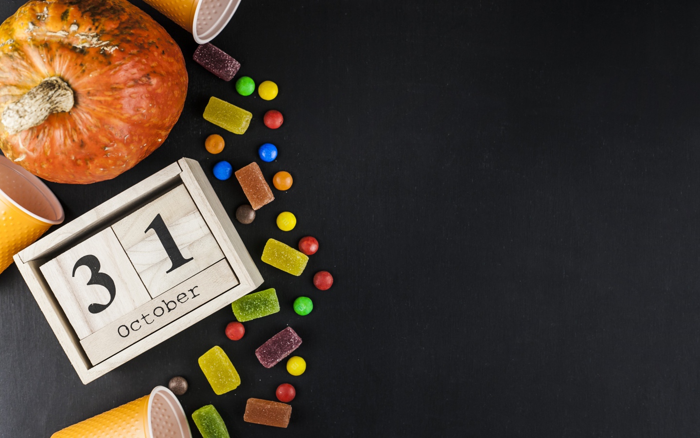 Конфеты, тыква и календарь на сером фоне на Хэллоуин