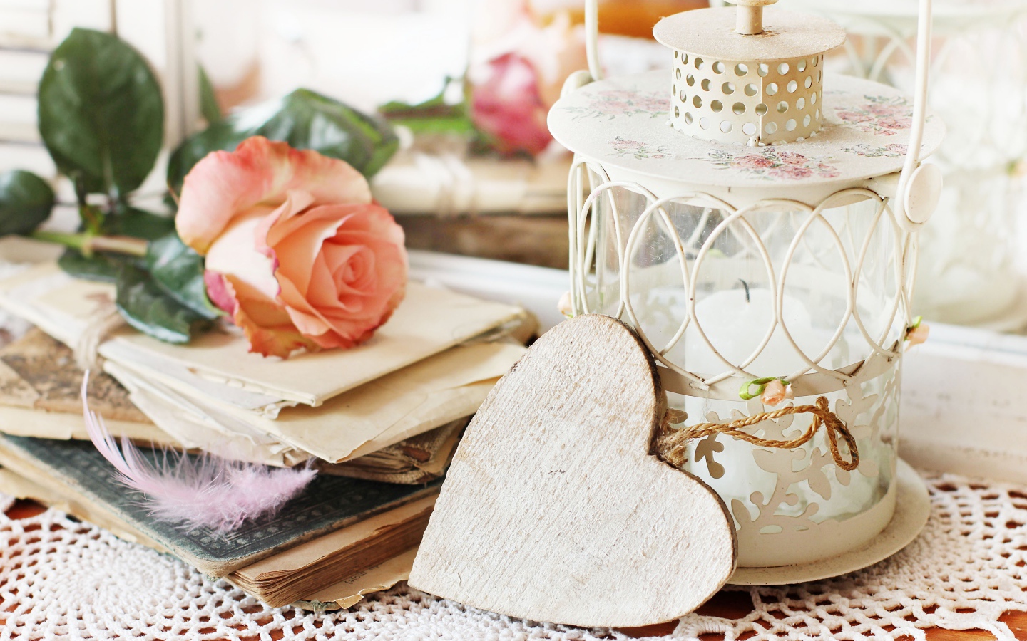 Фонарь со свечей на столе с розой, сердцем и книгами