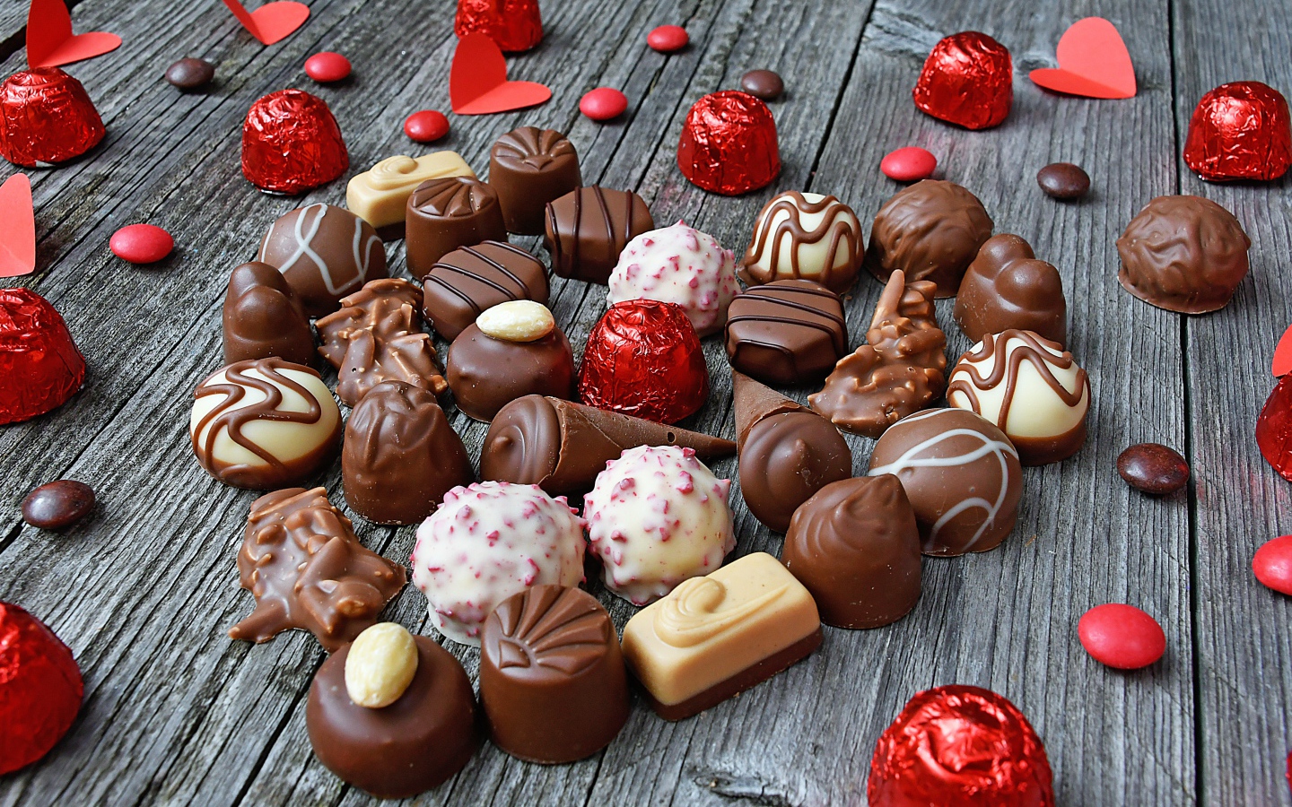 Сладкое сердце из шоколадных конфет на деревянном столе