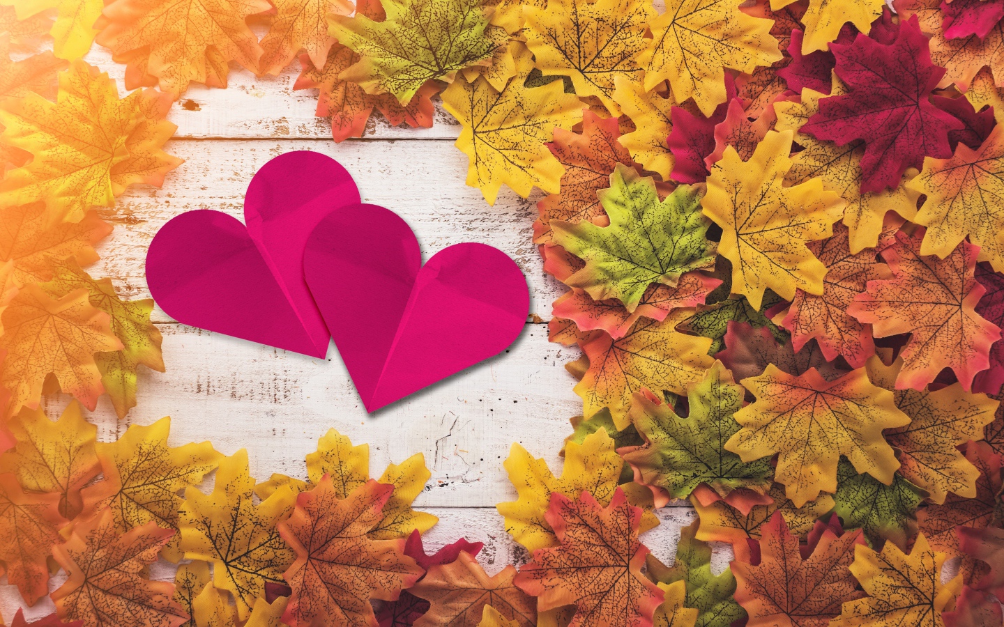 Два красных сердца на столе с желтыми листьями