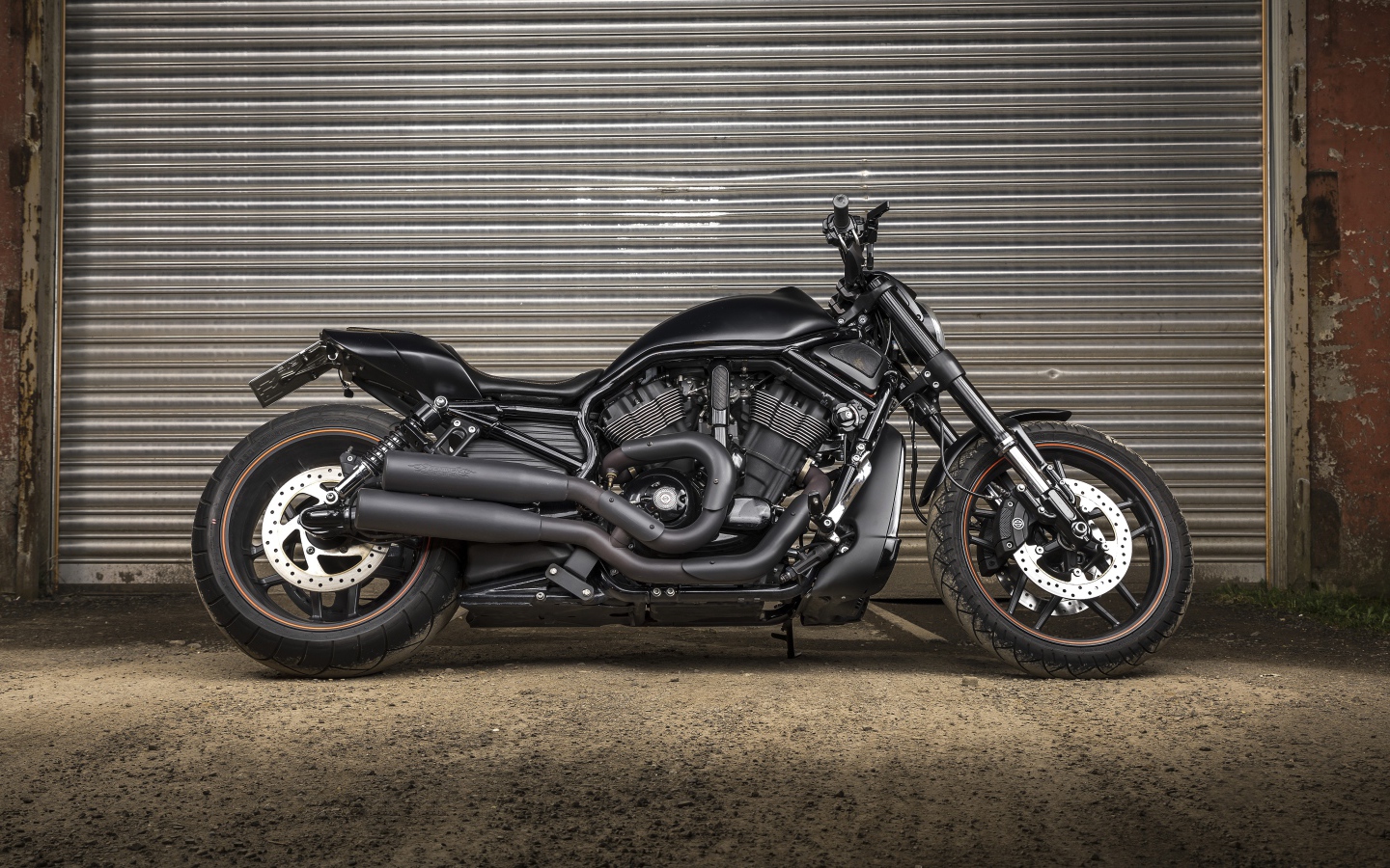 Черный тяжелый мотоцикл Harley-Davidson у гаража