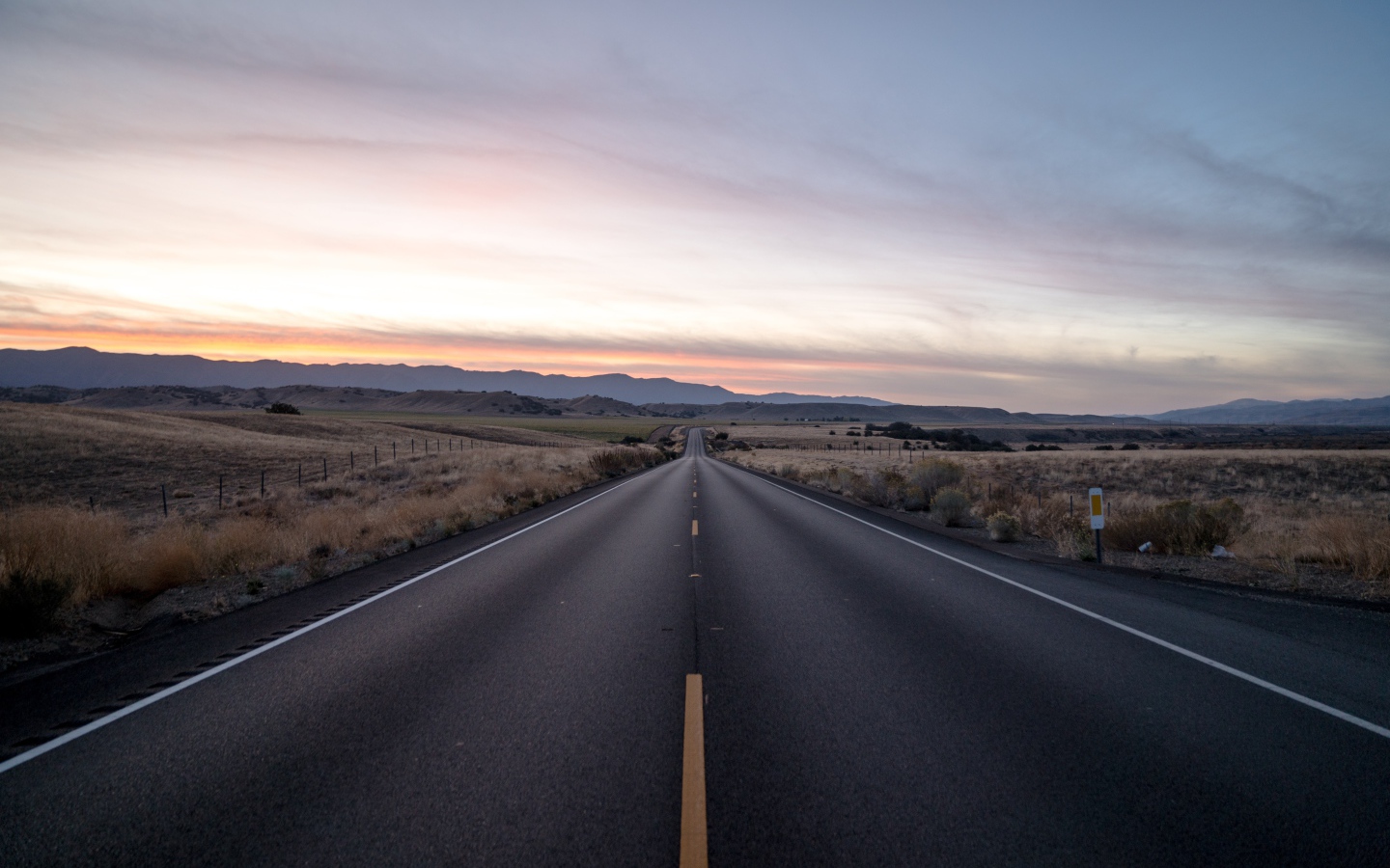 Асфальтная дорога уходит вдаль на фоне неба