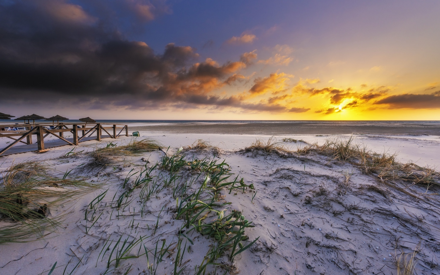 Белый песок в траве на берегу под красивым небом на закате