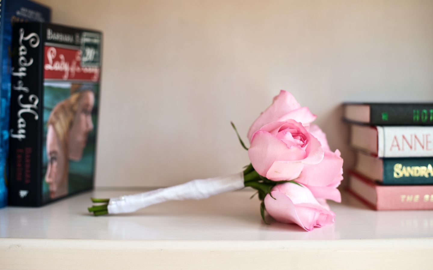 Букет розовых роз лежит на полке с книгами