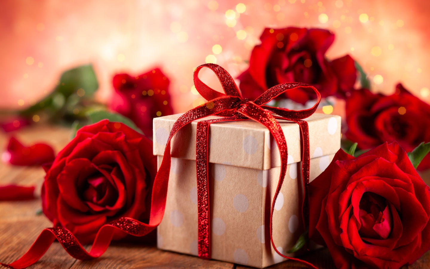 Подарок с красным бантом на столе с букетом роз