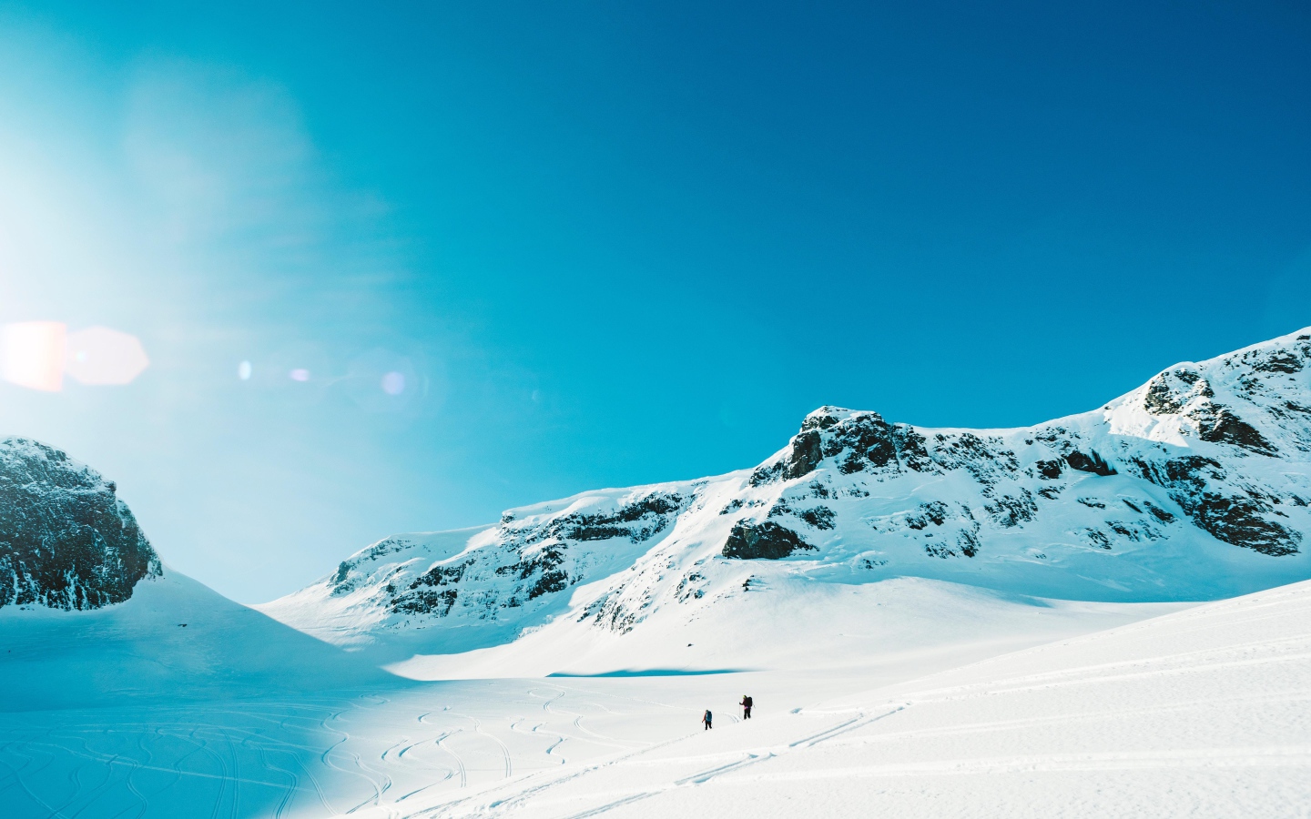 Красивые заснеженные горы под голубым небом в лучах солнца 