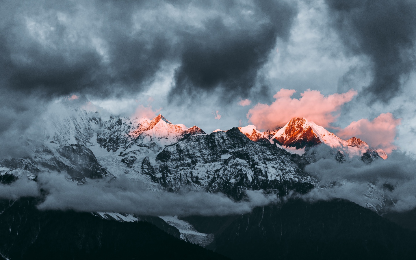 Солнце на рассвете освещает вершины заснеженных гор 