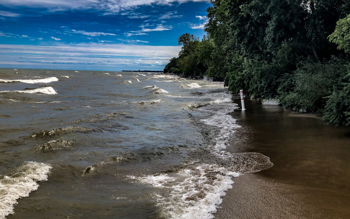 Морские волны омывают берег под голубым небом 