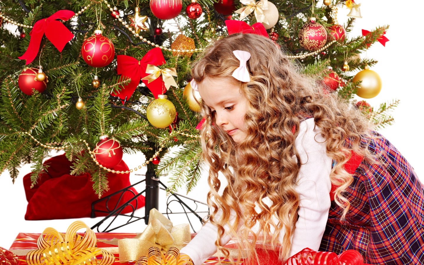 Красивая маленькая девочка смотрит подарки под елкой на новый год 