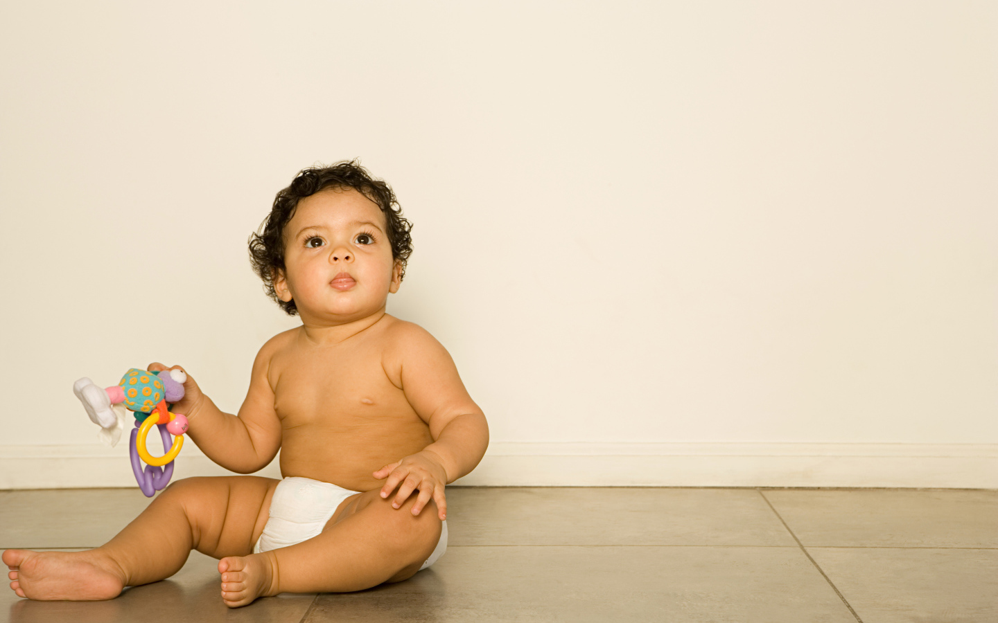 Маленький мальчик сидит на полу с игрушкой