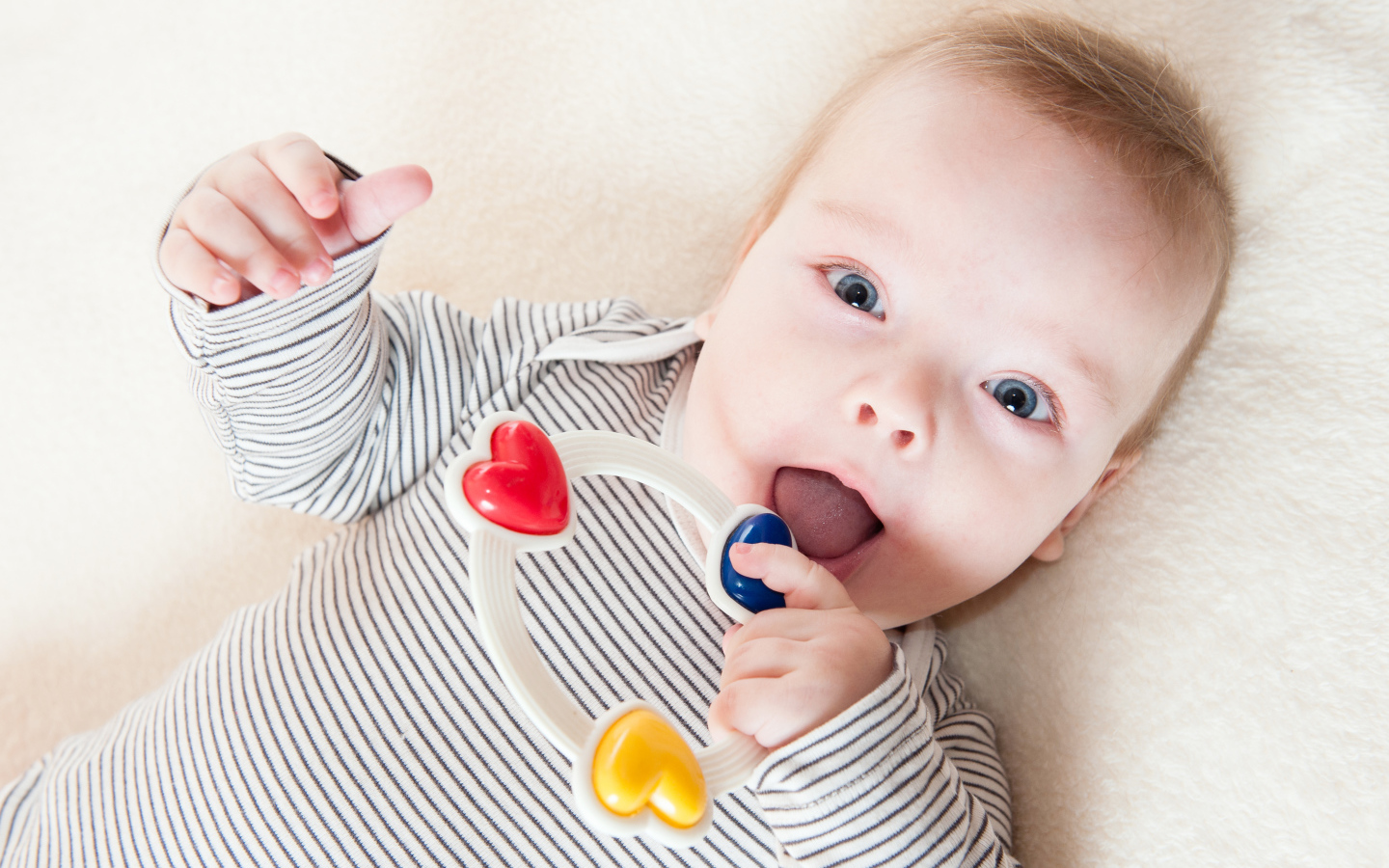 Маленький забавный голубоглазый ребенок с погремушкой