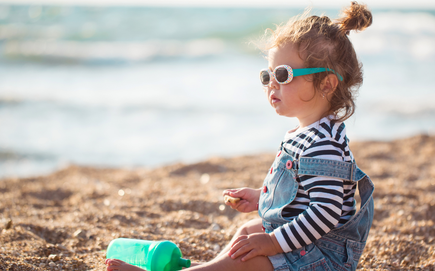 Маленькая девочка сидит на песке на пляже