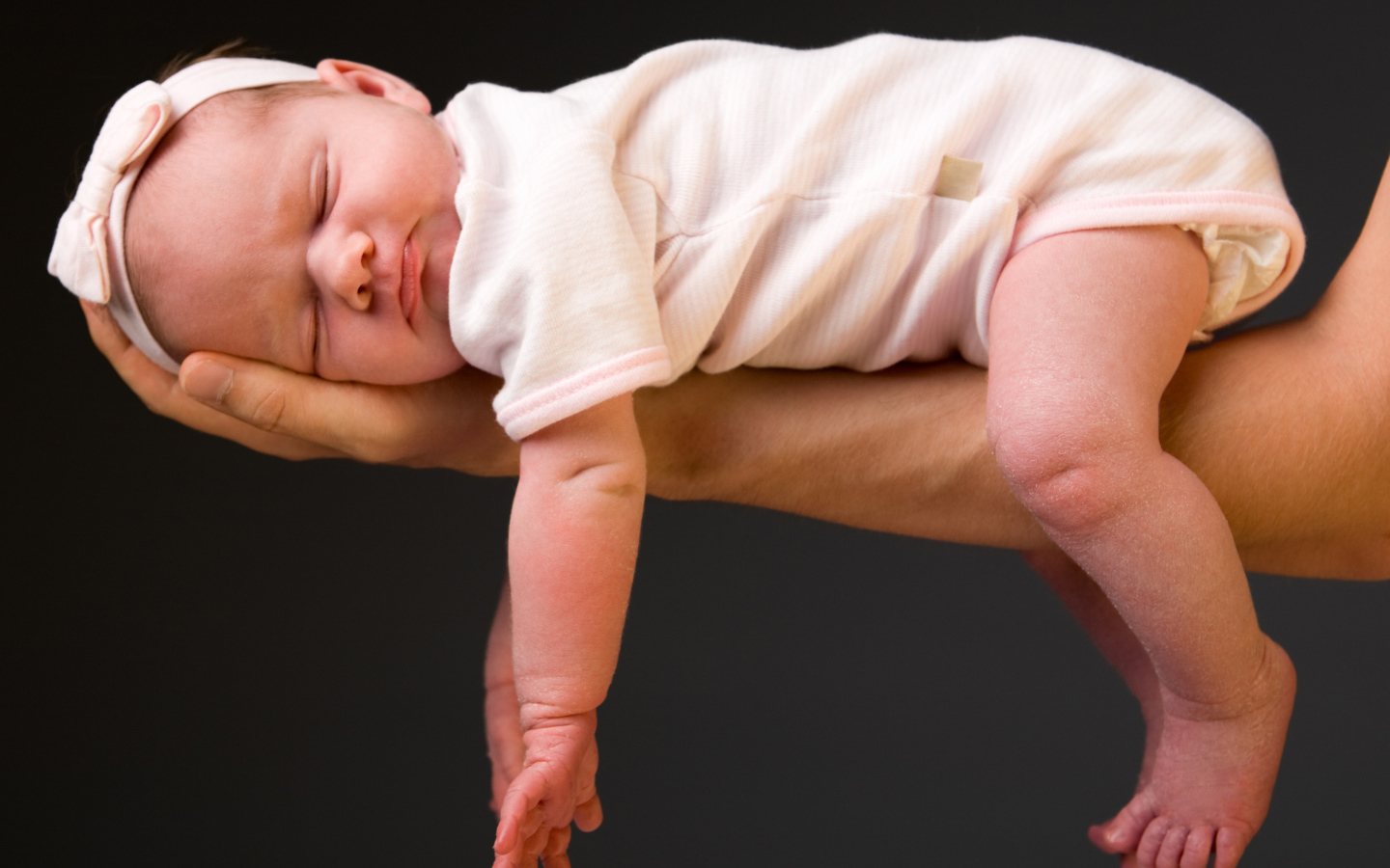 Спящий ребенок на руке у папы на сером фоне