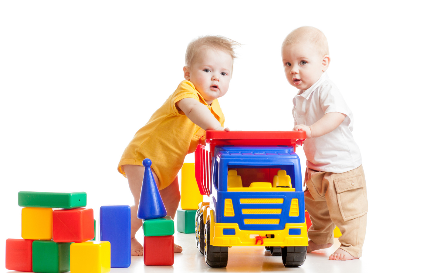 Два маленьких ребенка с игрушками на белом фоне