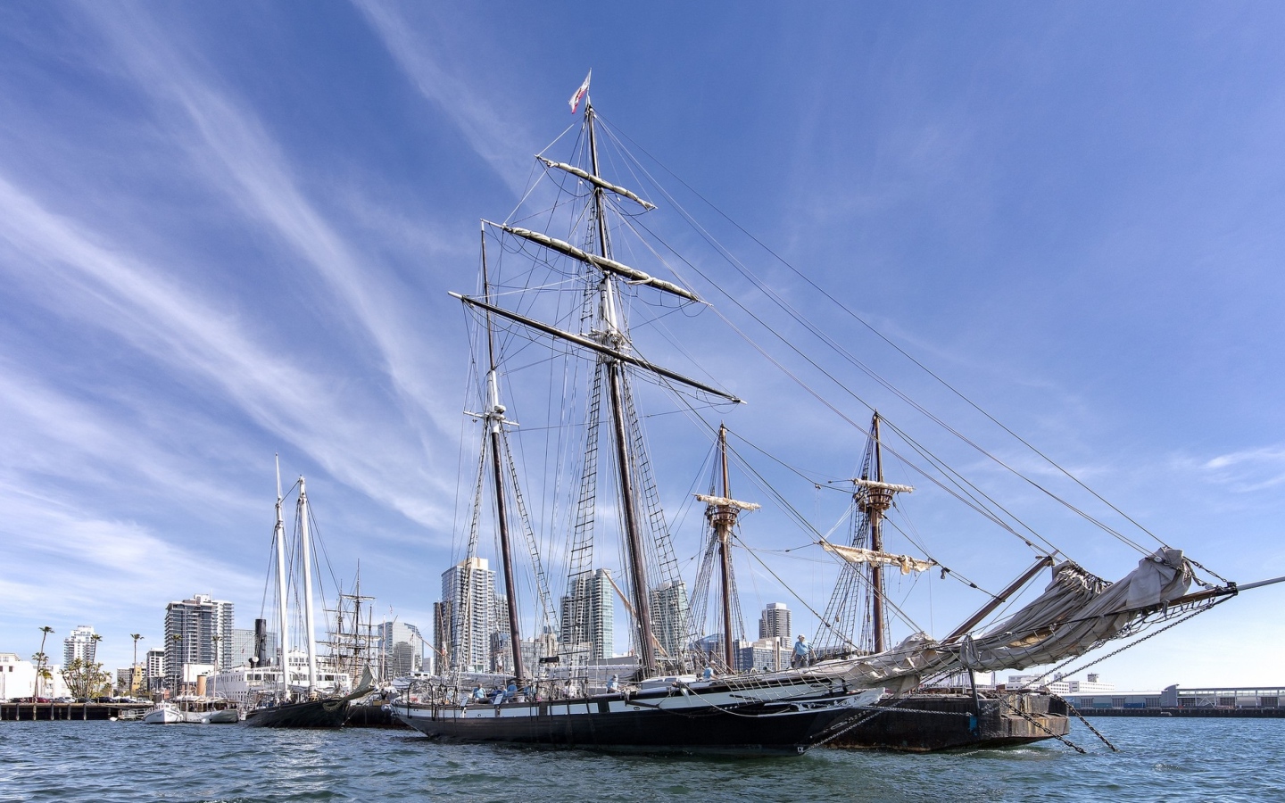 Большая парусная лодка на фоне голубого неба в порту у города