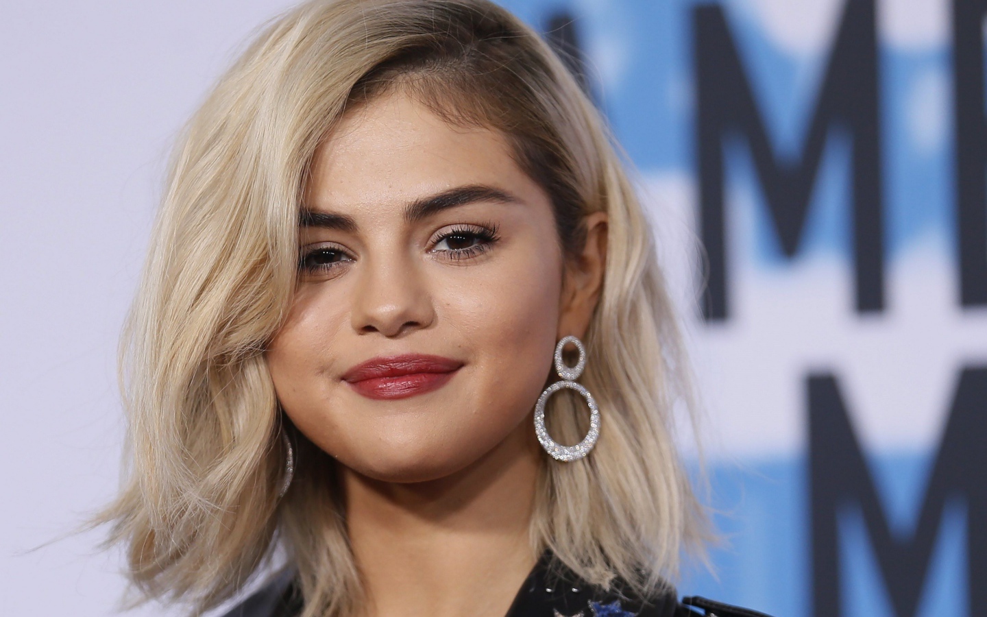 Красивая блондинка, актриса Селена Гомес с серьгами в ушах