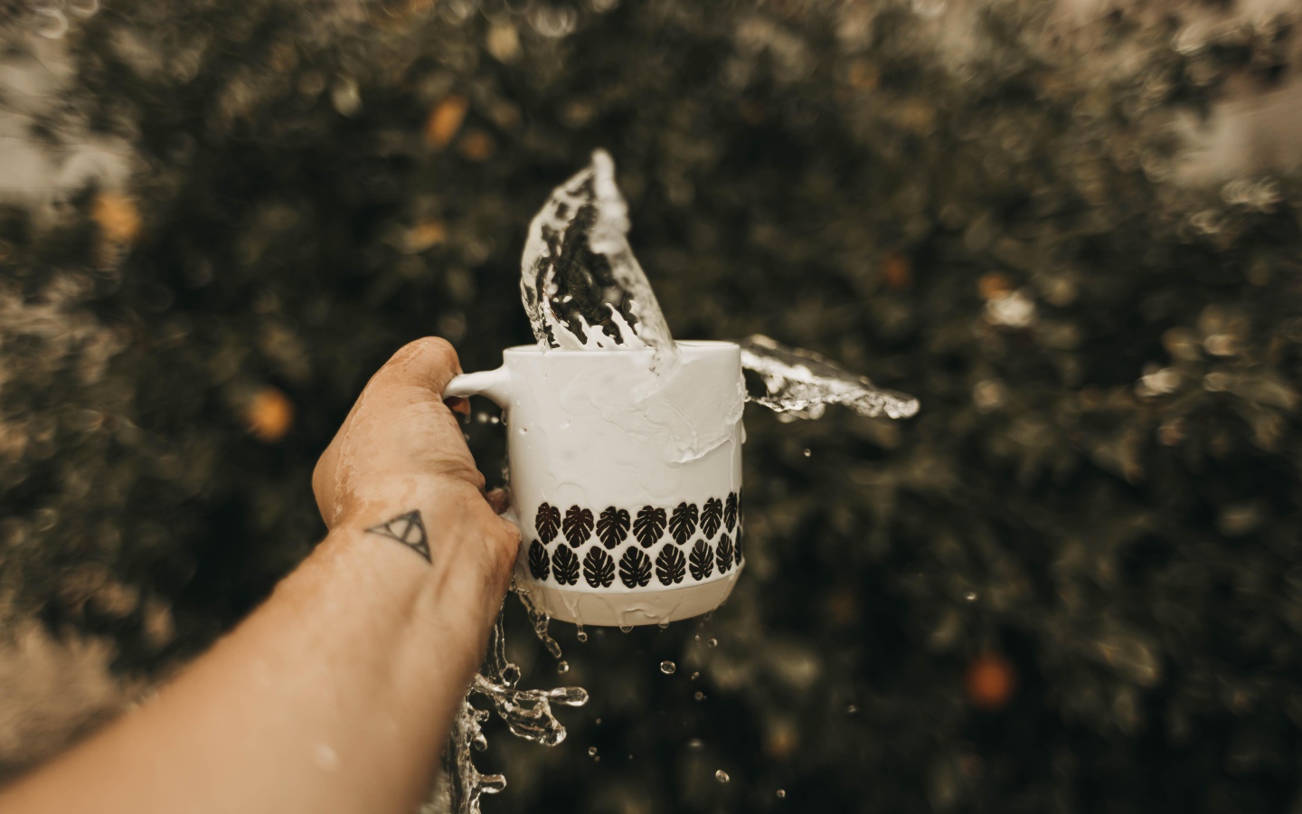 Чашка с водой в руке с татуировкой 