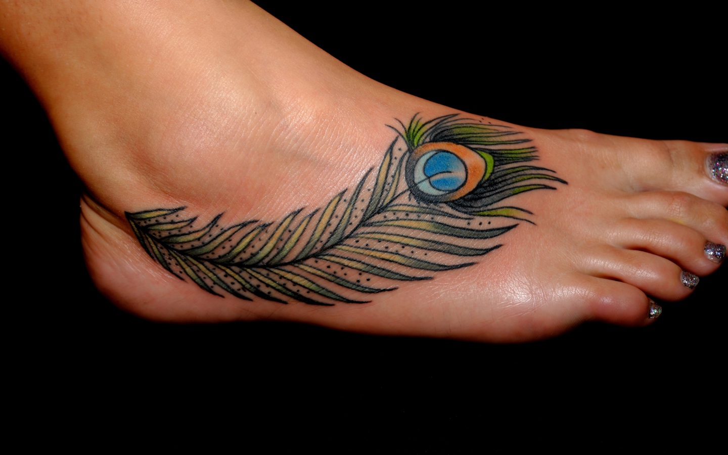 Татуировка перо павлина на ноге на черном фоне