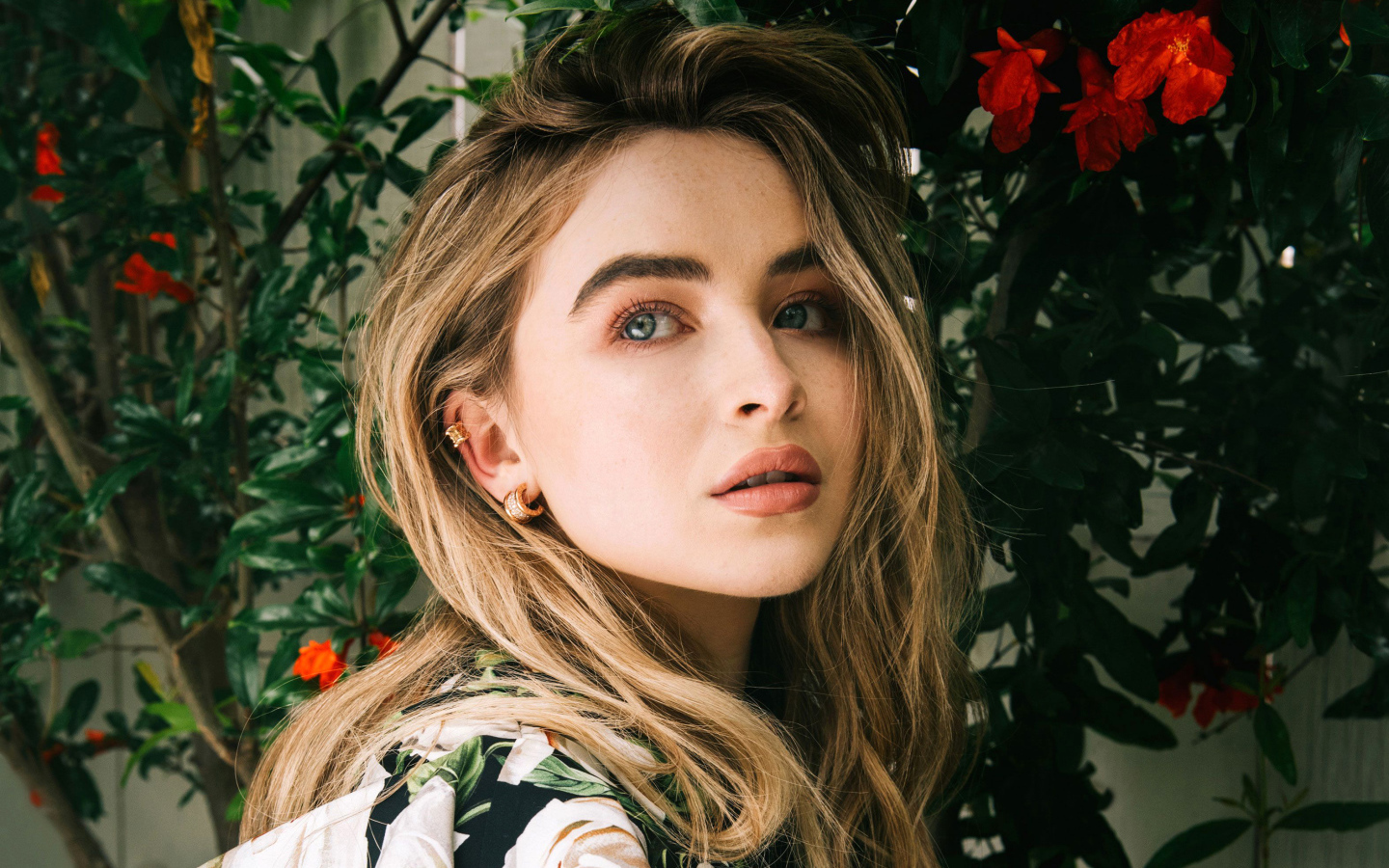 Молодая красивая актриса Сабрина Карпентер у красных цветов