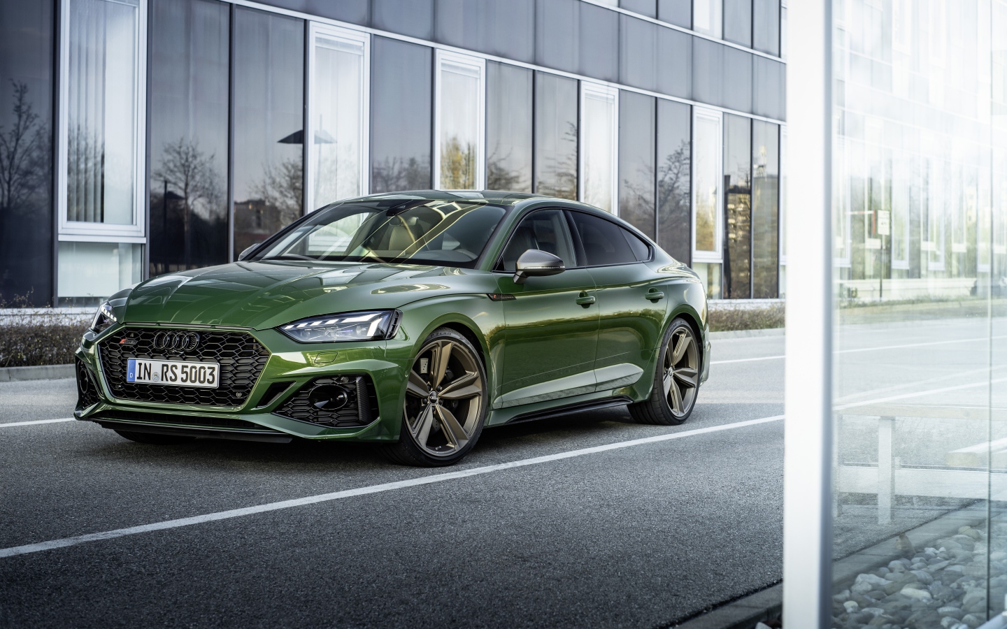 Зеленый автомобиль Audi RS 5 Sportback 2020 года у здания 