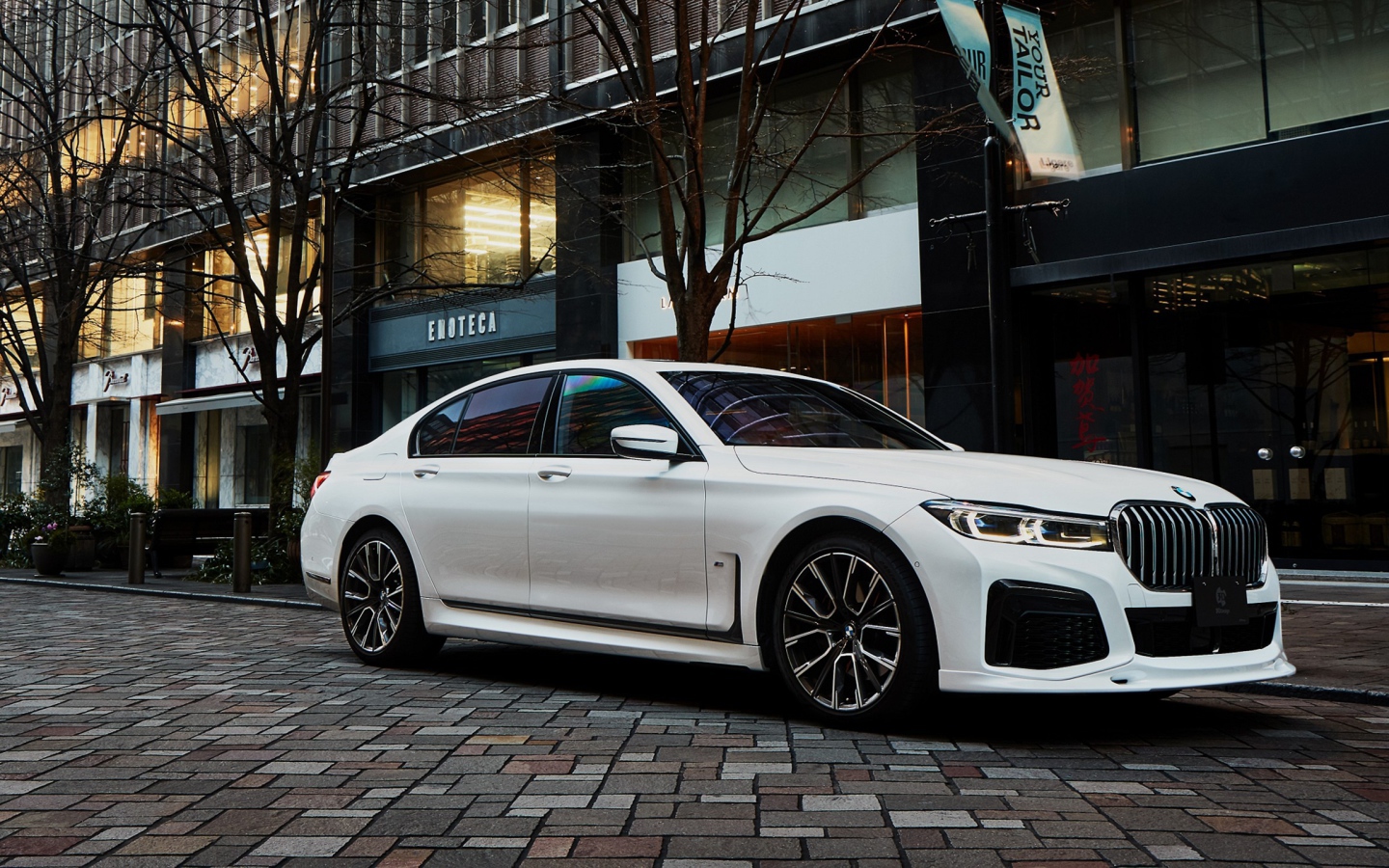 Белый автомобиль  BMW 740i M Sport 2020 года у кафе