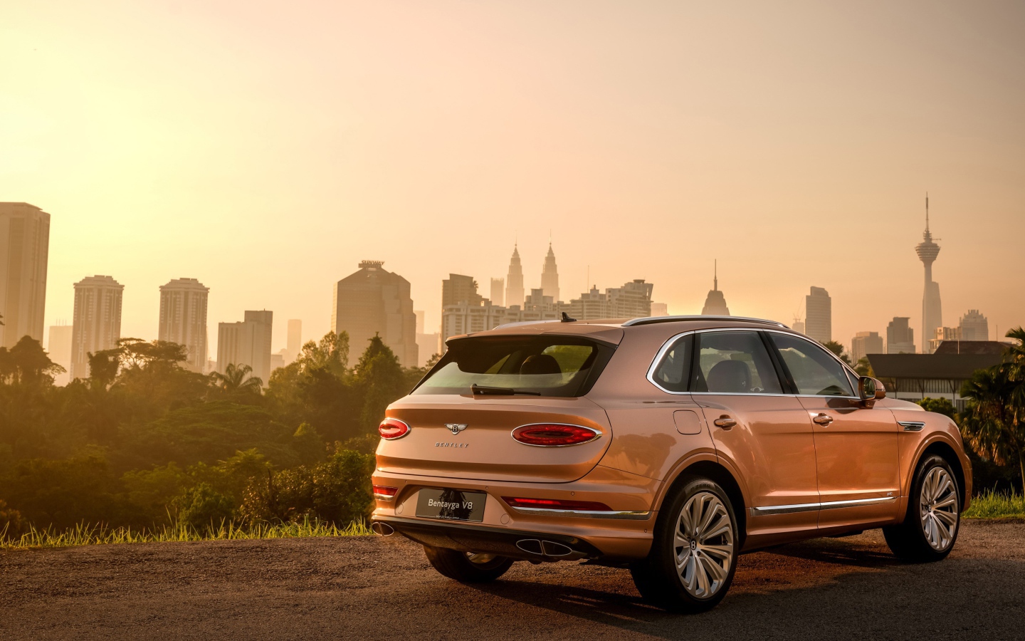 Автомобиль Bentley Bentayga V8 2020 года вид сзади на фоне города 