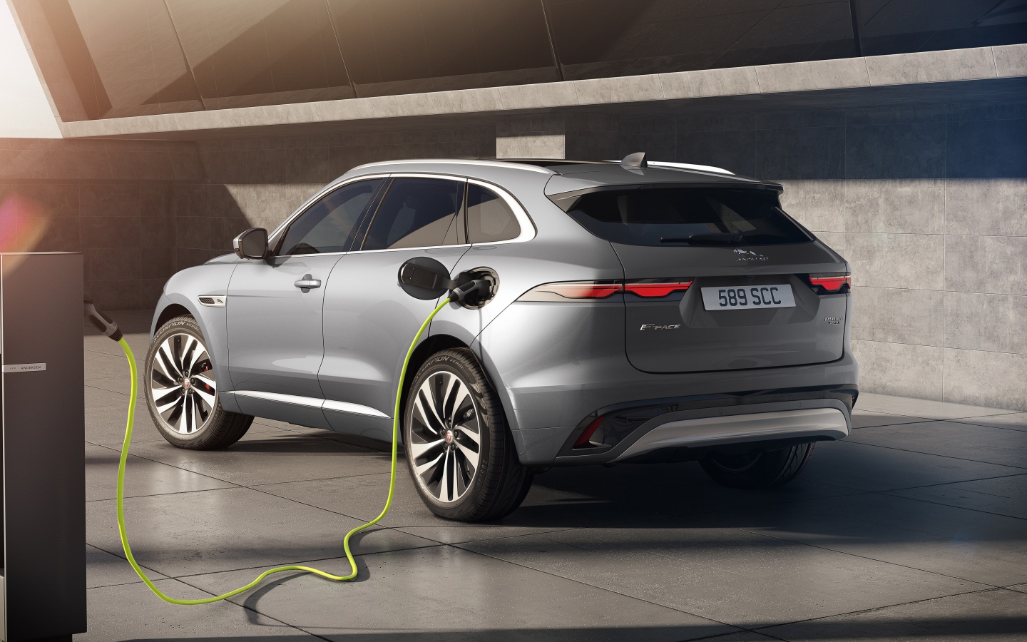 Серебристый автомобиль Jaguar F-Pace P400e AWD 2020 года на заправке 