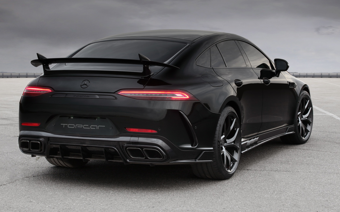 Черный автомобиль Mercedes-AMG GT 63 S 4MATIC+, 2020 года вид сзади на сером фоне