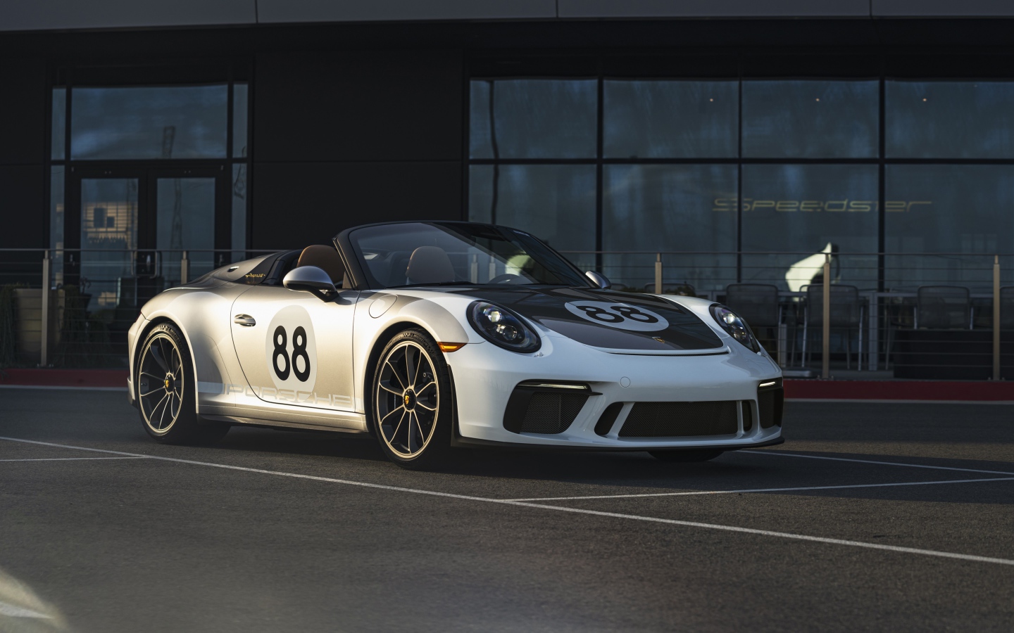 Спортивный автомобиль Porsche 911, 2019 года у стеклянного здания