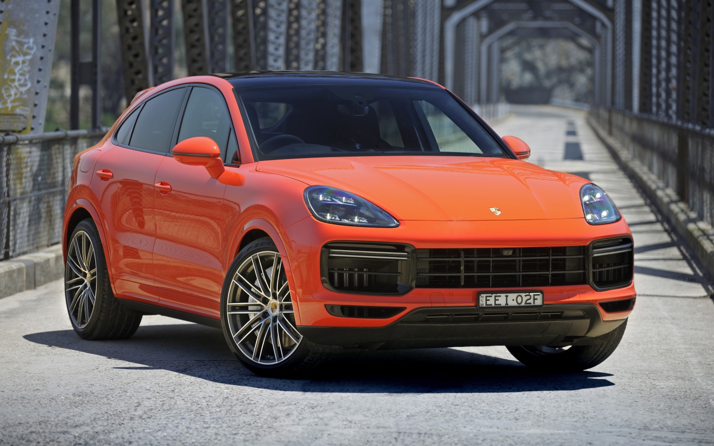 Оранжевый внедорожник Porsche Cayenne Turbo Coupe 2019 года на мосту