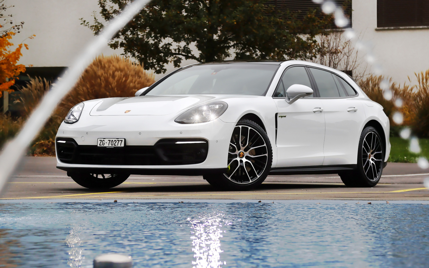Белый автомобиль Porsche Panamera 4S E-Hybrid Sport Turismo 2020 года у бассейна