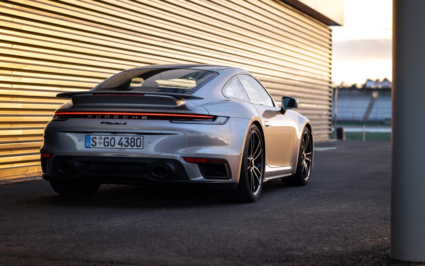 Серебристый автомобиль Porsche 911 Turbo S 2020 года у гаража
