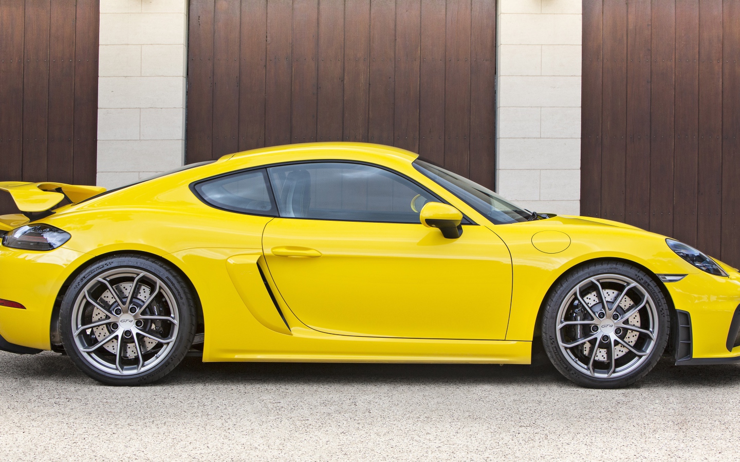 Желтый автомобиль Porsche 718 Cayman GT4 2020 года вид сбоку