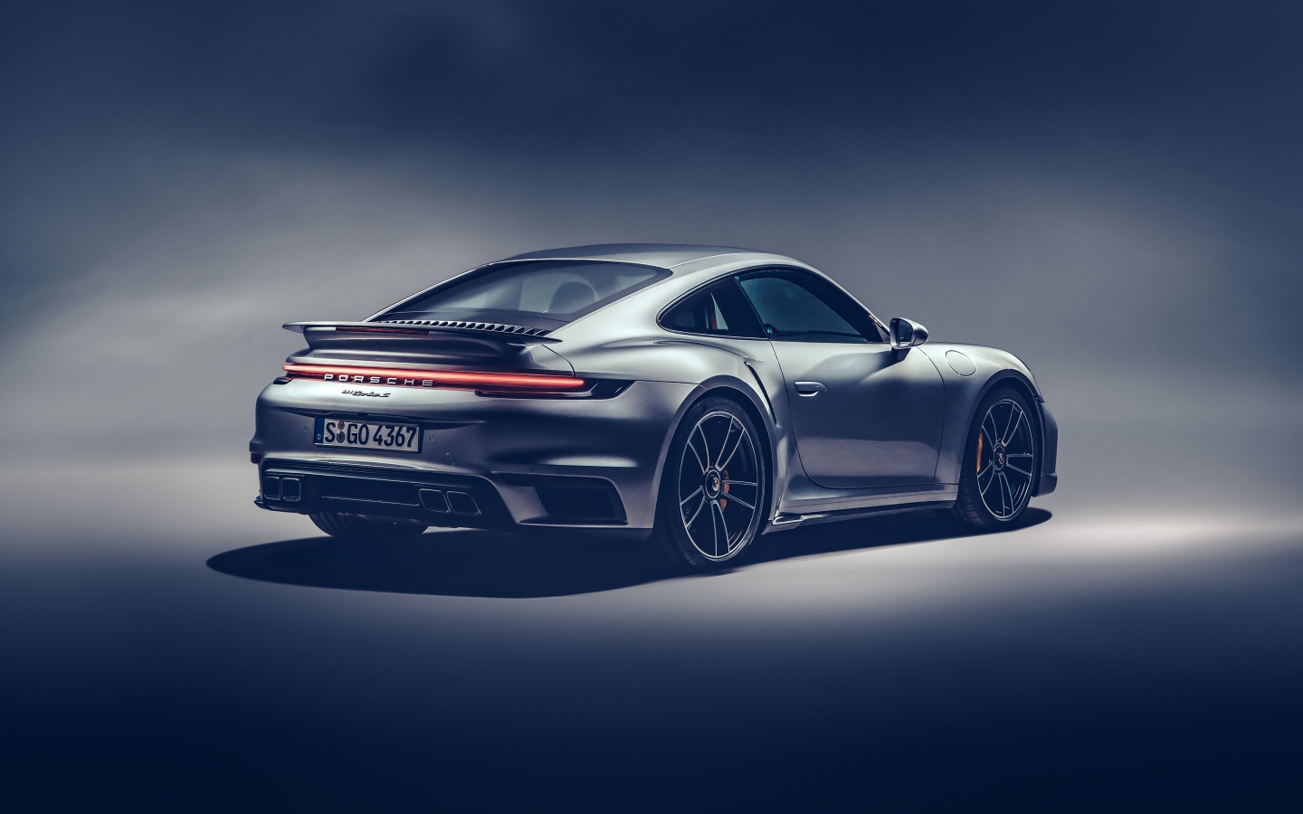 Автомобиль Porsche 911 Turbo S 2020 года на сером фоне вид сзади