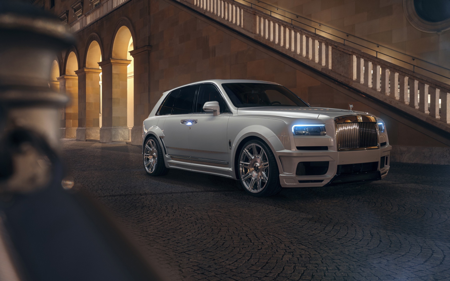 Белый автомобиль  Rolls-Royce Cullinan 2020 года у лестницы