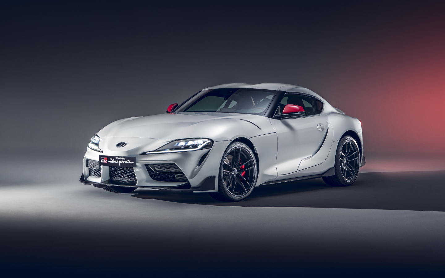 Серебристый автомобиль Toyota GR Supra 2L 2020 года на сером фоне