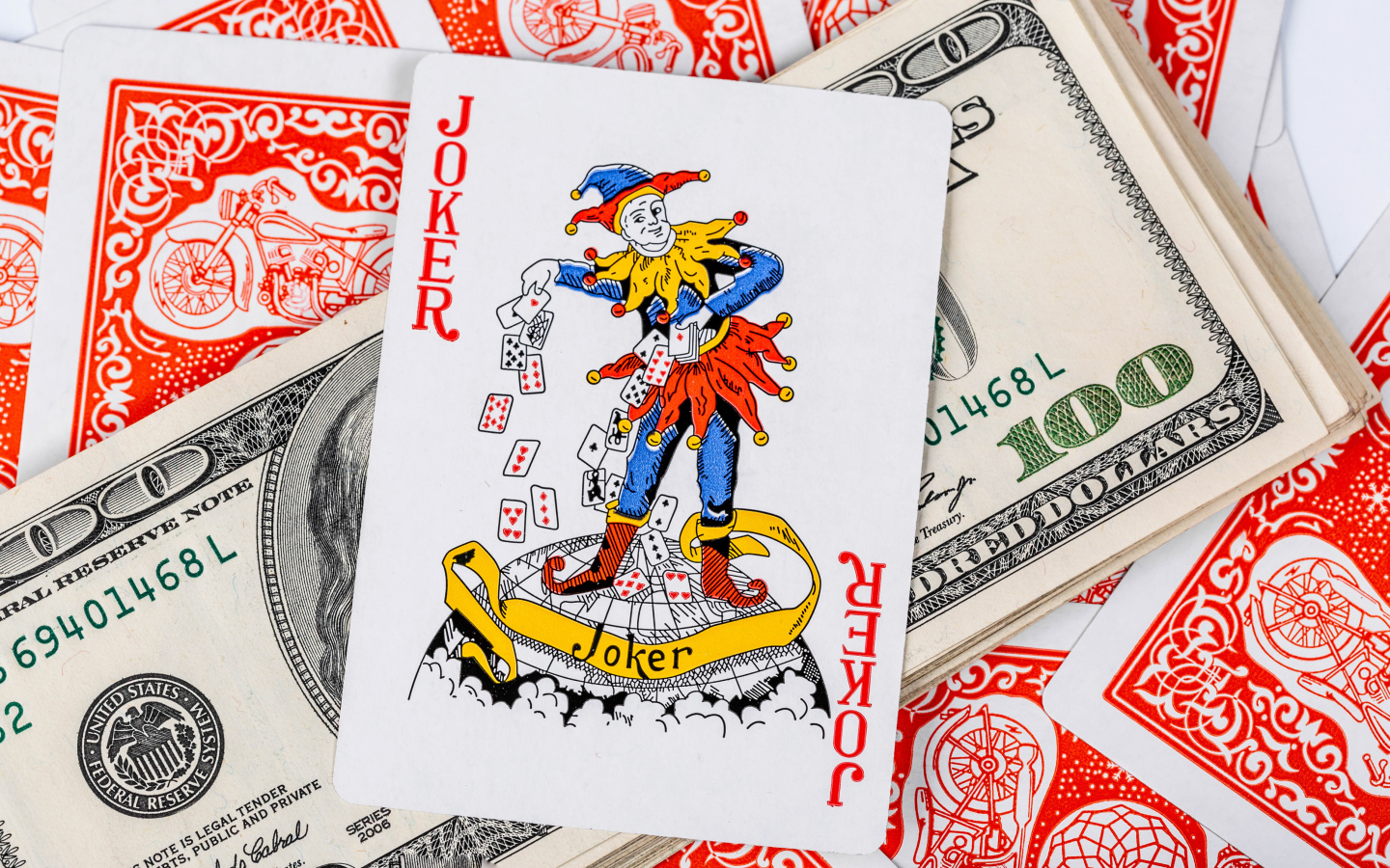 Карточный Джокер и пачка стодолларовых купюр