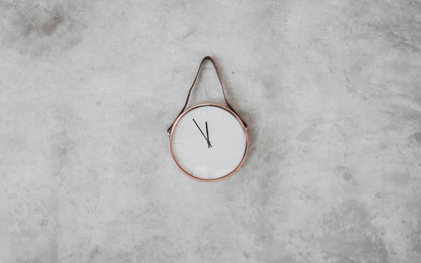 Часы с черными стрелками висят на серой стене 