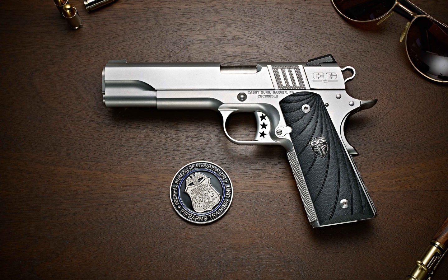 Пистолет Cabot 1911 лежит на столе с очками и жетоном 