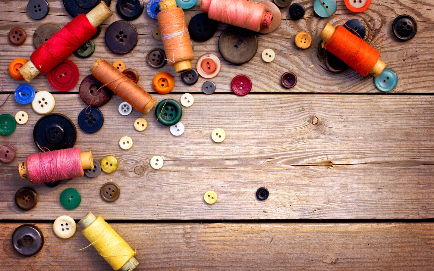 Разноцветные пуговицы и нитки лежат на столе