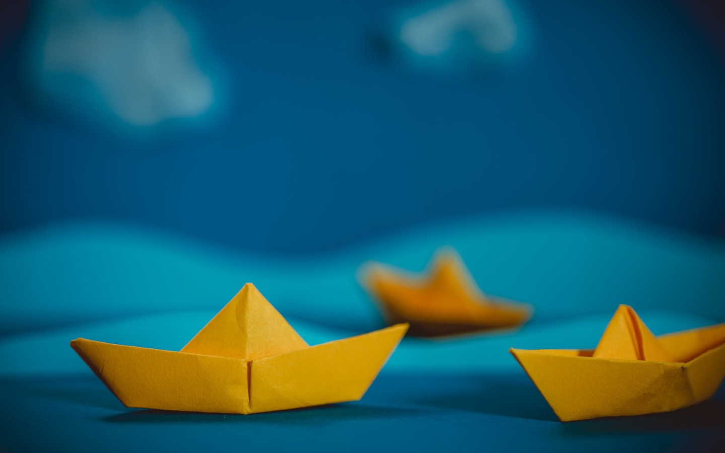Yellow origami boats on a blue background
