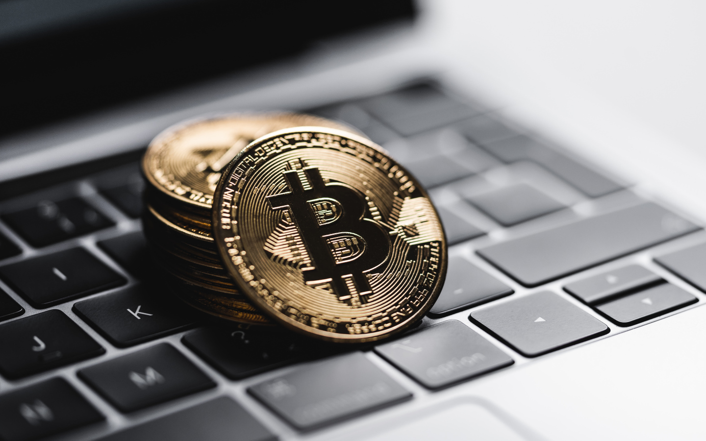 Монеты биткоин лежат на клавиатуре ноутбука 