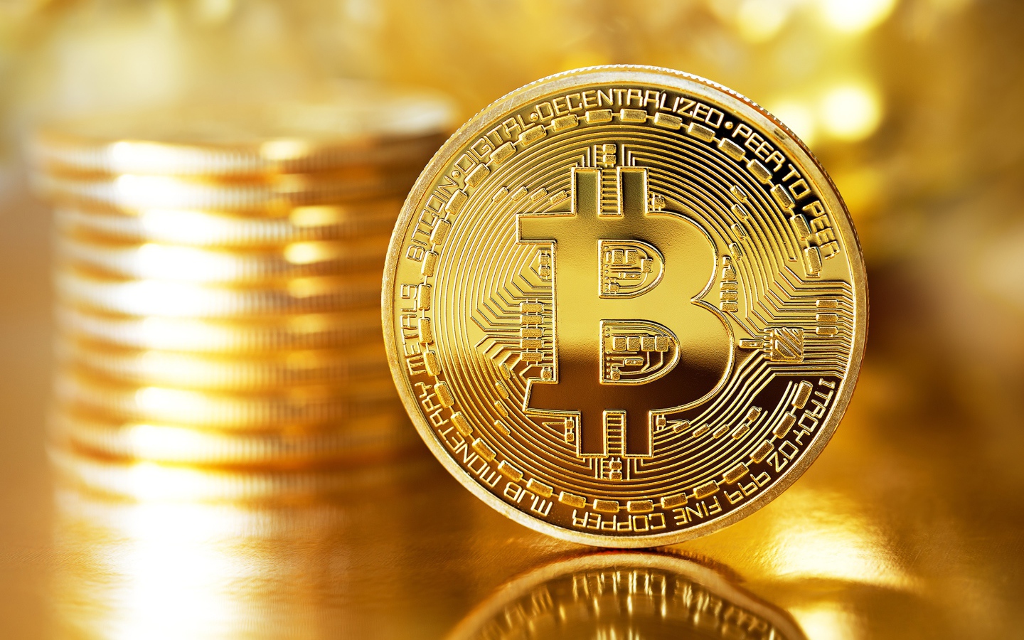 Золотая монета биткоин отражается в поверхности стола 