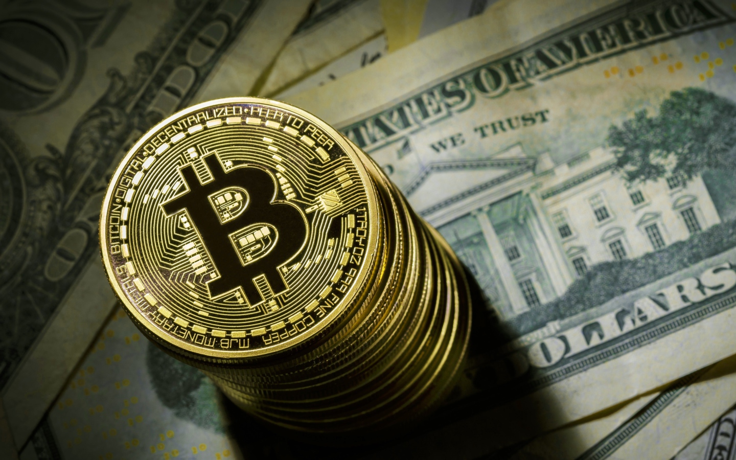 Золотые монеты биткоин лежат на долларах