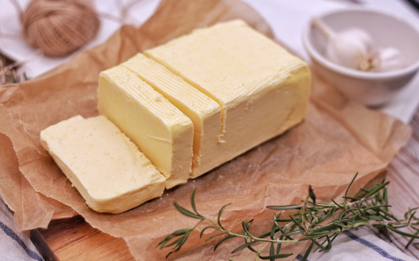 A piece of fresh butter on the table with rosemary and garlic