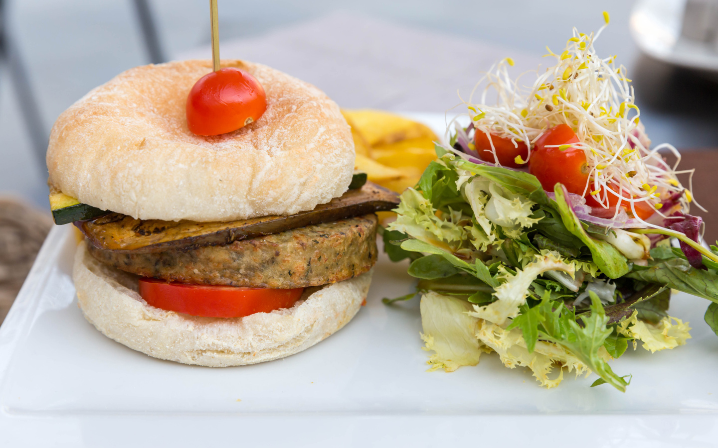 Большой гамбургер с салатом на столе 