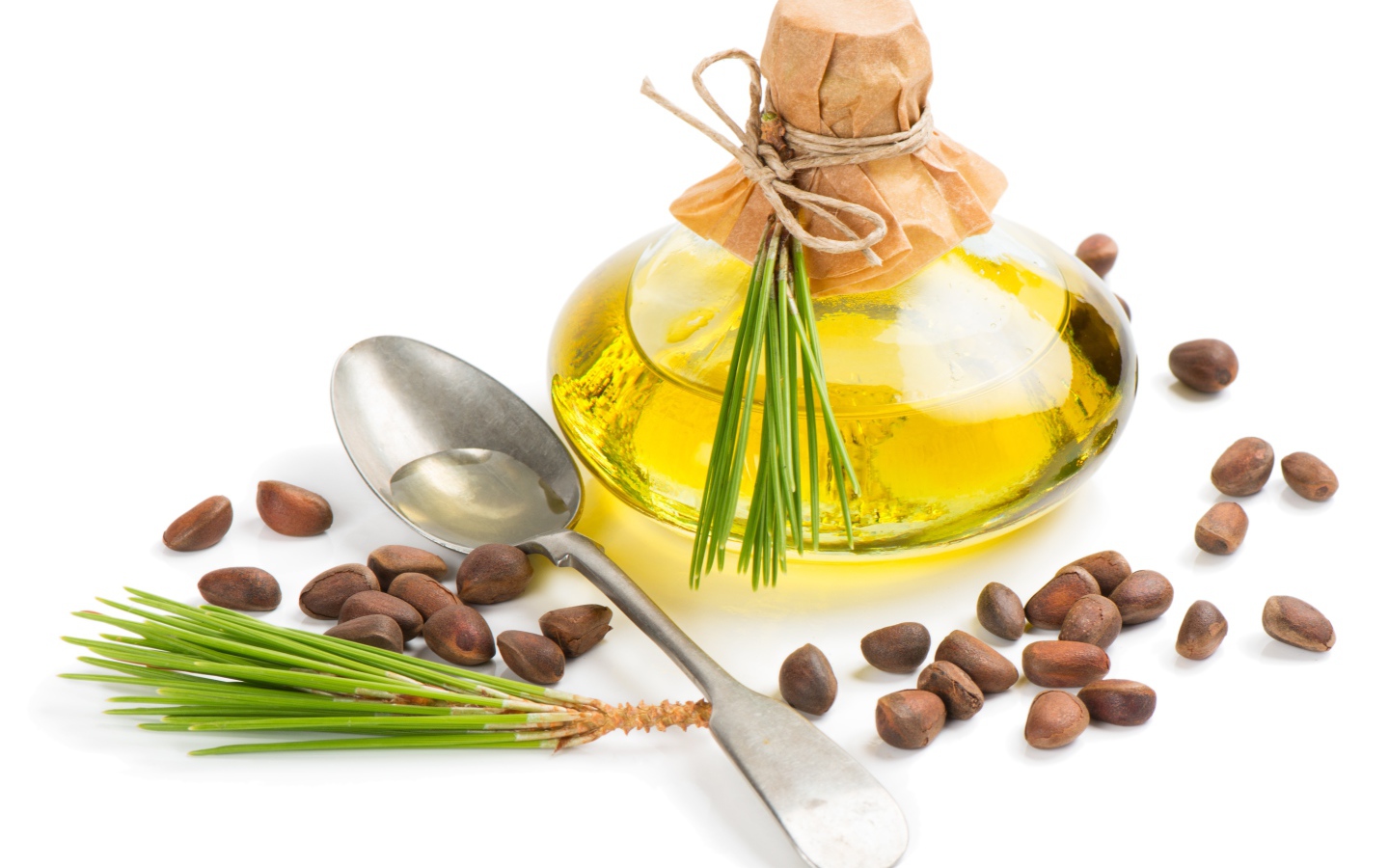 Кедровое масло на белом фоне с орехами и ложкой
