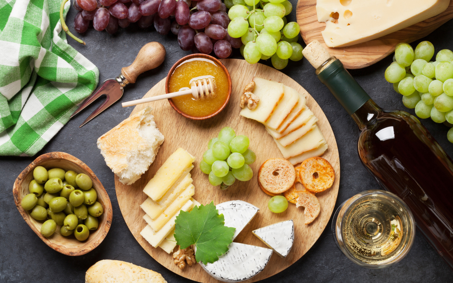 Сыр на столе с виноградом, оливками и белым вином