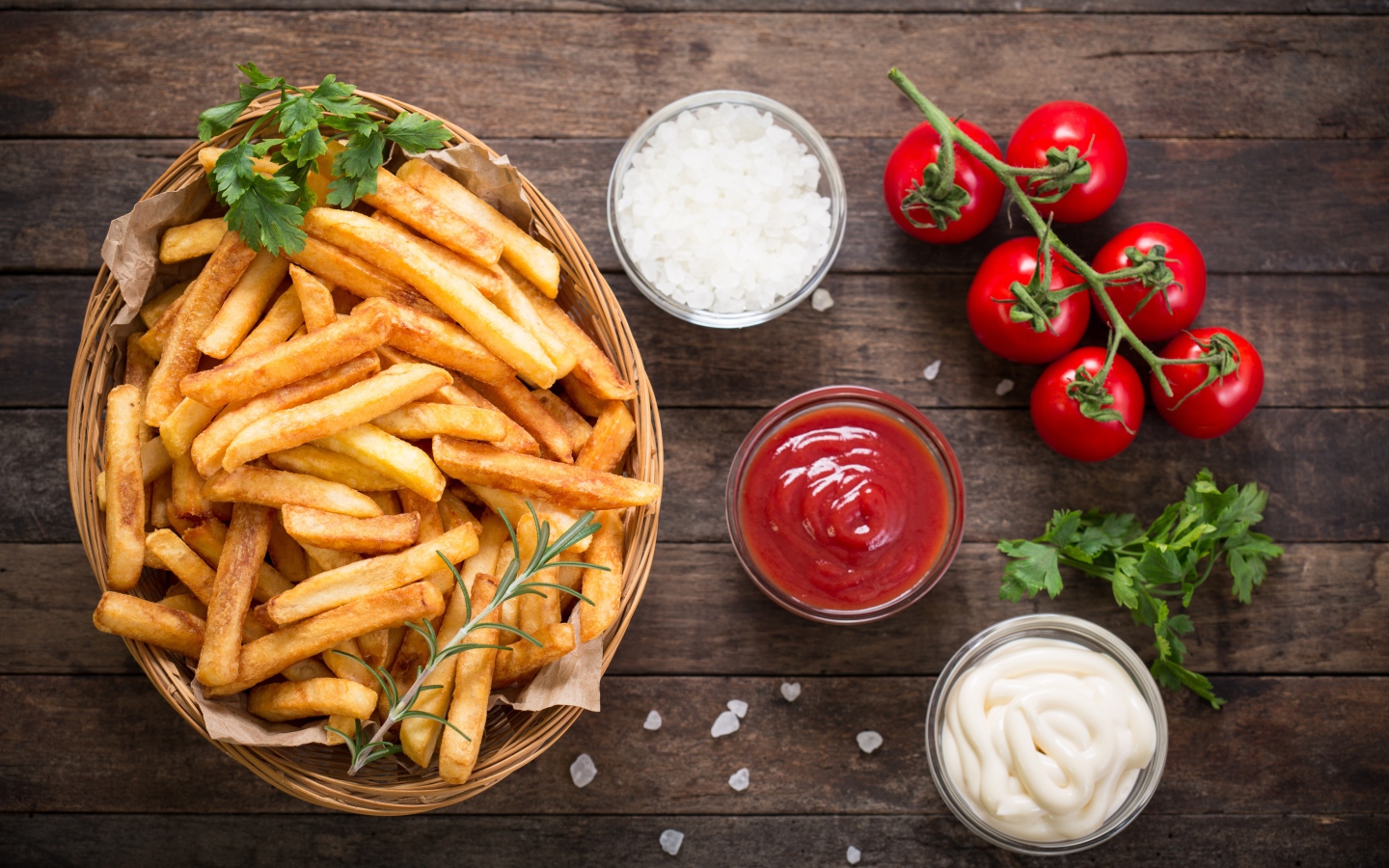 Картофель фри на столе соусом, солью и помидорами 