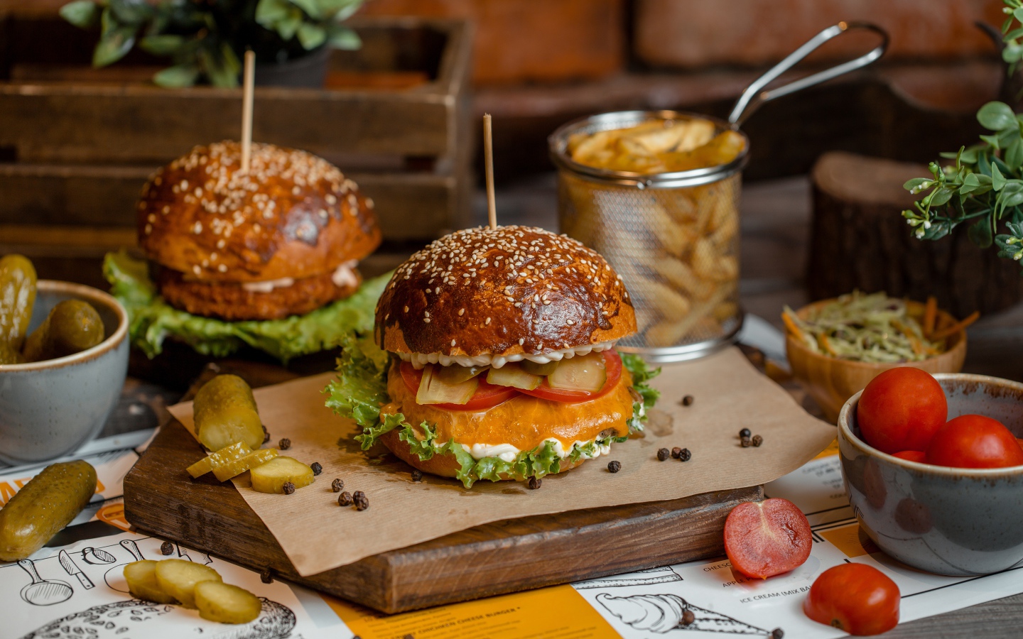 Гамбургеры на столе с помидорами, картофелем фри и солеными огурцами